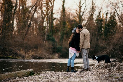 A Caucasian pregnant woman and her man walking with a dog in the park and doing some maternity photoshoot.