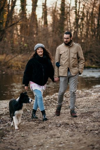 A vertical shot of a Caucasian pregnant woman and her man walking with a dog in the park and doing some maternity photoshoot.