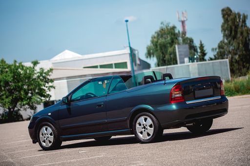 A dark green cabriolet car parked during daytime
