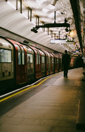 A rear shot of a man standing near the empty train on the subway, Kings Cross, London,