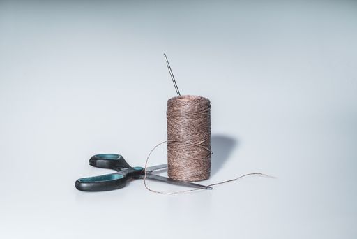 a closeup shot of brown twine and scissors on a white surface