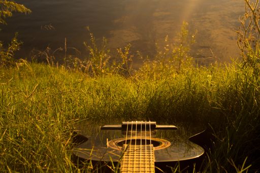 A closeup shot of a guitar on the grass - perfect for background