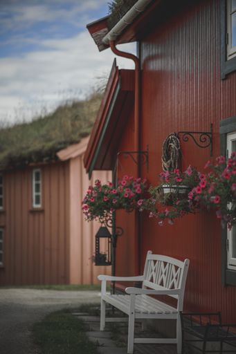 A view of a white bench near the red house with flowers