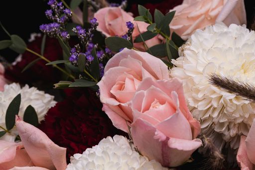 A closeup shot of a luxurious bouquet of pink roses and white flowers on a black background