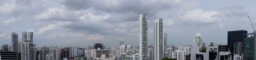 A panoramic shot of Singapore skyline with skyscrapers and cloudy sky