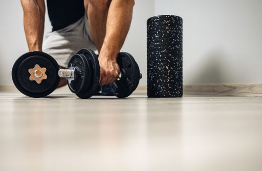A male hand holding dumbbells on the floor