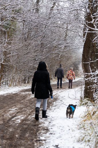 A woman and child holding hands and walking on a wet footpath in the Rusalka park