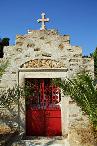 A vertical shot of the stone brick wall with a red door of the monastery of Agios Ioannis Theologos