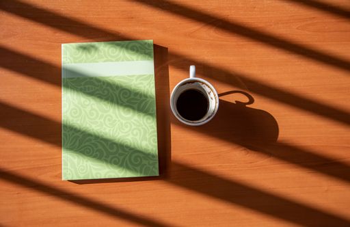 A book and a cup of Turkish coffee on a wooden table with beautiful sunlight