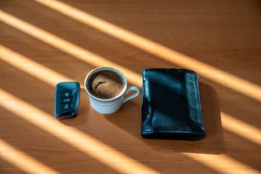 A Turkish coffee cup, car key, and black full wallet on wooden table with copy space
