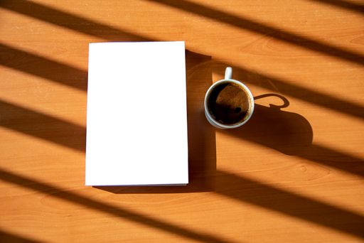 A book and a cup of Turkish coffee on a wooden table with beautiful sunlight