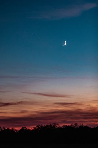 A vertical shot of a moon in a sunset sky over Wisconsin