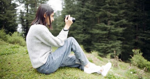 An Indian woman taking photos with a camera in the forest