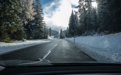 A shot on the move from behind the windshield of an electric car with snow-covered alps mountains. Cold cloudy autumn day