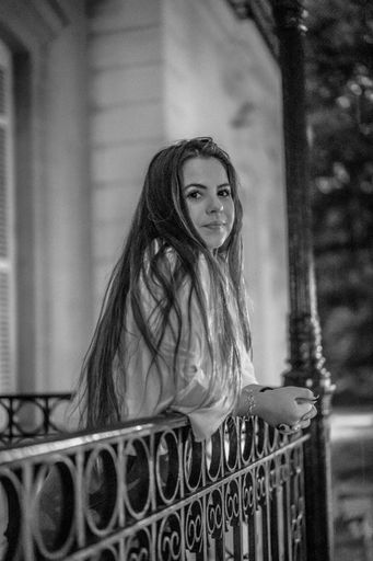 A grayscale shot of a young brunette Caucasian female posing for the camera in the city of San Sebastian Spain