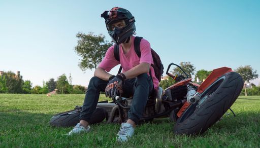 A view of a motorcyclist sitting on an orange bike, wearing a helmet and gloves