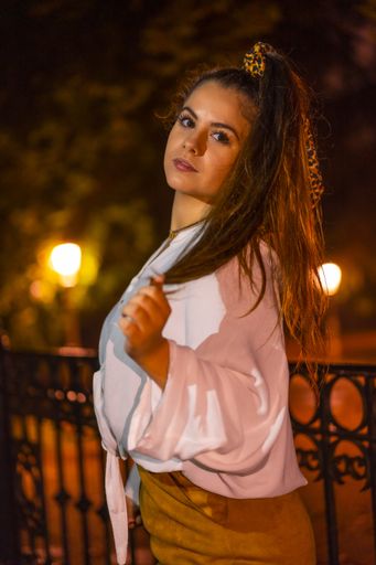 A selective focus shot of a young Caucasian brunette female wearing a hair scarf in the city of San Sebastian at night