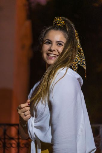 A selective focus shot of a young Caucasian brunette female wearing a hair scarf in the city of San Sebastian at night