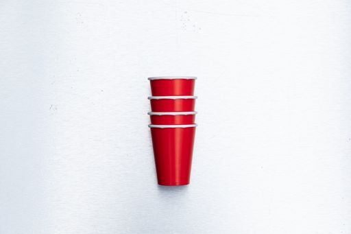 A closeup vertical shot of red paper cups set isolated on a white background- recycled paper cups concept