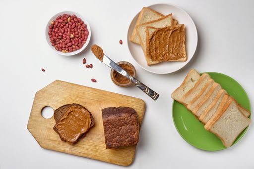 The peanut butter, slices of buttered bread and peanuts isolated on a white background