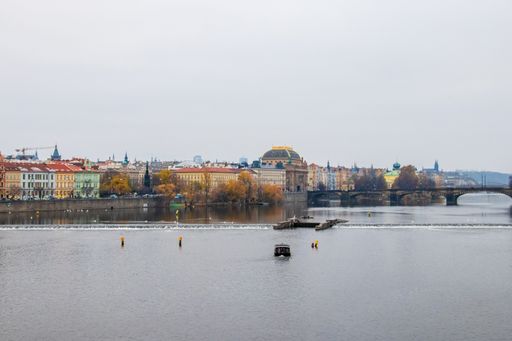 The Vltava River surrounded by trees and buildings under a cloudy sky in Prague, the Czech Republic