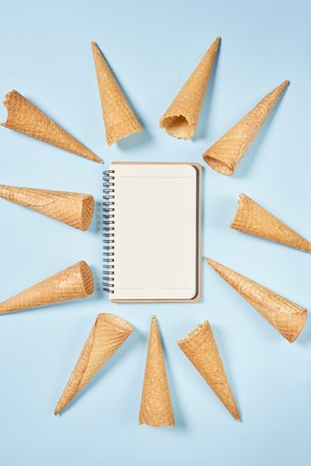 A top view shot of ice cream cones and a notebook on a blue background with copy space