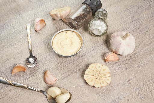 A closeup shot of different spices, a sauce and spoons on the wooden surface