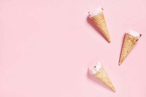 A top view of refreshing strawberry ice-creams in waffle cones over the pink surface