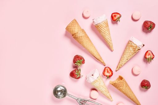 A top view shot of of ice cream cones and strawberries on a pink background with copy space