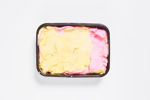 A top view shot of colorful ice cream in a black bowl on a white background