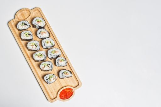 A top view of the fresh and appetizing maki sushi rolls served with red caviar on a wooden plate