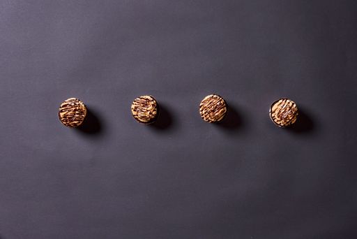 A top view of tasty cupcakes with a chocolate cream topping over the gray surface