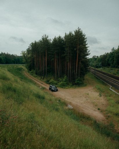 A vertical shot of the car parked near the forest.