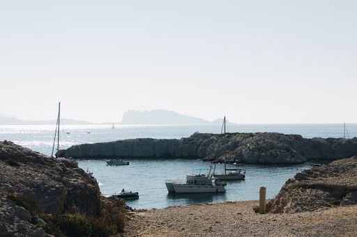 A wide shot of boats on the body of water near rock formations under a clear sky