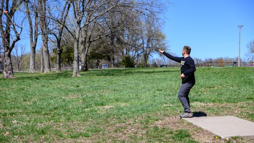 A disc golf player throwing a disc in the park.