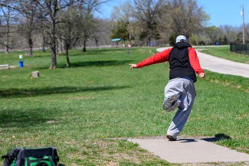 A disc golf player throwing a disc in the park.