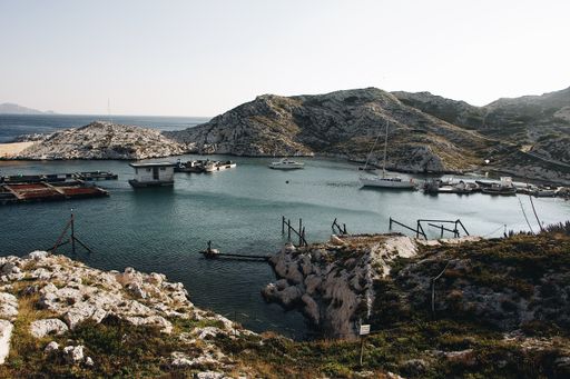 A wide shot of various boats and docks on the body of water surrounded by mountains and cliffs