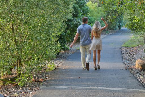 A back view of a happy couple holding hands and walking in a park