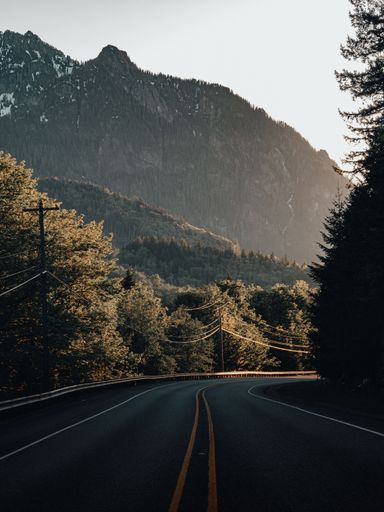A vertical shot of a long road through rural mountain areas in Washington