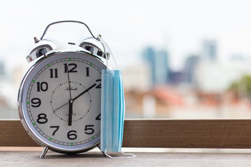 A closeup shot a metallic alarm with a medical mask hanging on it