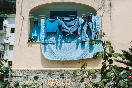 A low angle shot of blue laundry hanging from lines on a balcony
