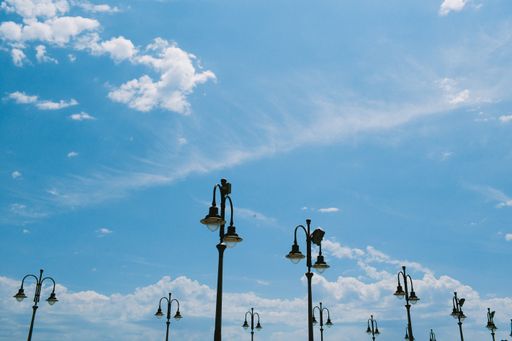 A low angle shot of street lamps in a blue sky
