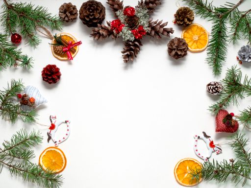 A top view of pine branches and Christmas ornaments on a white surface with copy space