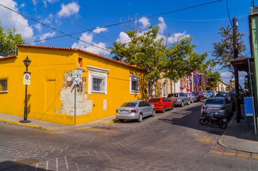 Candid street photography of parked cars and colorful houses in the colonial style in Oaxaca, Mexico