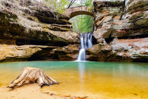 A waterfall with long exposure surrounded by rocks in Hocking Hills State Park, the US