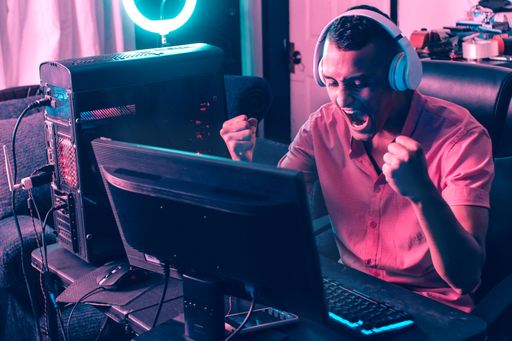 A young latin arms making a winner gesture in front of a gamer computer