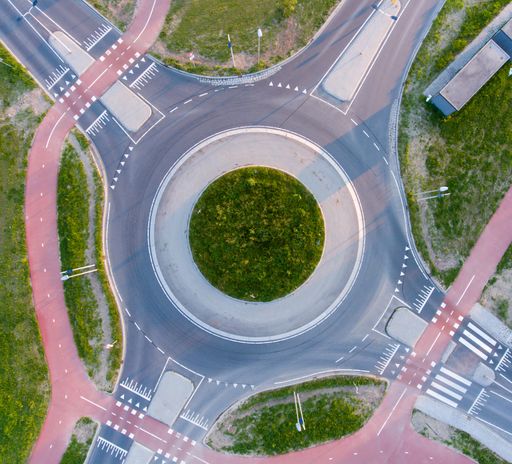 An aerial shot of a roundabout surrounded by greenery under the sunlight at daytime