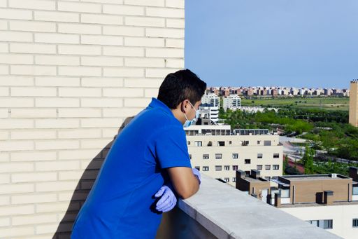 A horizontal shot of a male in quarantine on their terrace using protective measures