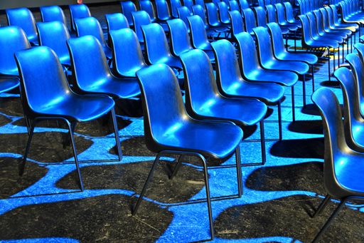 A view of empty audience seats arranged in rows under the blue  flashlights