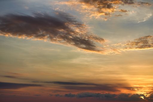 A scenic view of fluffy clouds changing colors at sunset